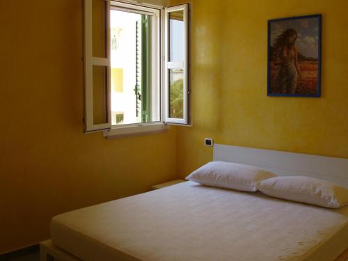 una camera da letto con un letto con due cuscini e una finestra di Residence Ammiraglia Baia Verde a Gallipoli
