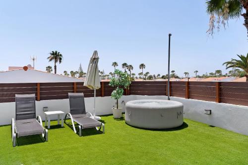 a patio with a table and chairs and an umbrella at Casa Luna Kingbed and Jacuzzi in Maspalomas