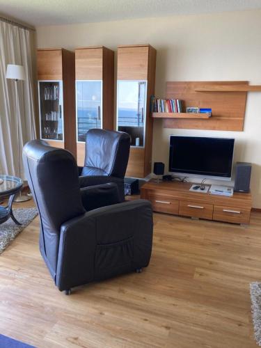 uma sala de estar com 2 cadeiras e uma televisão de ecrã plano em Ferienwohnung Schwitzkowski em Glücksburg