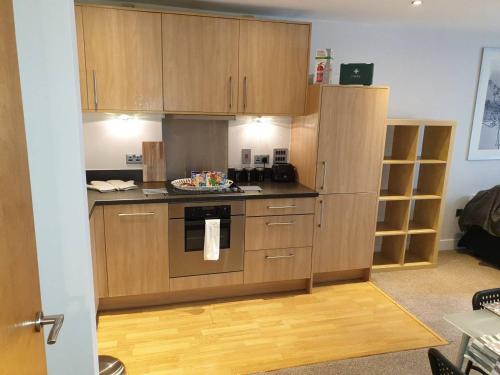 eine Küche mit Holzschränken und einem Backofen in der Unterkunft Birmingham Garnet 3-bedroom Apartment City Centre in Birmingham