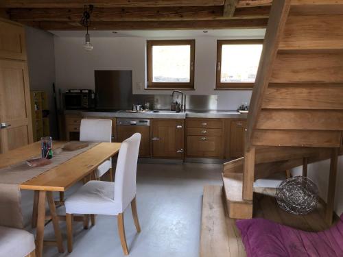 cocina con mesa de madera y sillas blancas en Sérénité et nature dans une ferme équestre, en Massonnens