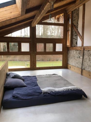 uma cama grande num quarto com janelas em Sérénité et nature dans une ferme équestre em Massonnens