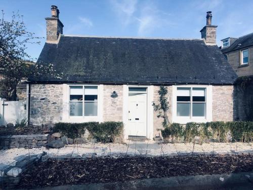 une maison en briques avec une porte blanche dans l'établissement Galashiels Town Centre Cottage Sleeps 2, à Galashiels