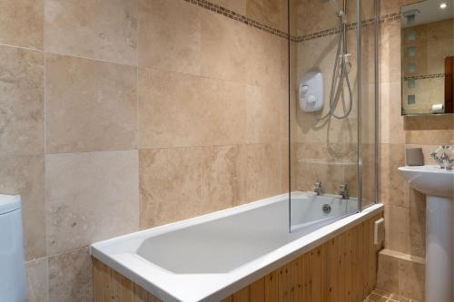 a bathroom with a tub and a sink at Honey Buzzard Farmhouse in Ilfracombe