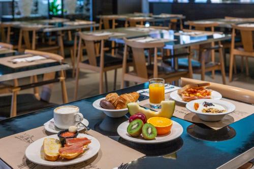 a table with plates of breakfast foods and orange juice at Porcel Torneo in Seville