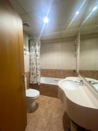 a bathroom with a sink and a toilet and a tub at Lovely 2BR Al Deyafa in Dubai