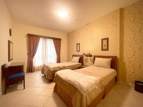 ドバイにあるLovely 2BR Al Deyafaのベッド2台と窓が備わるホテルルームです。