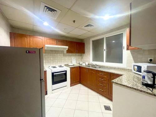 a kitchen with wooden cabinets and a white appliance at Lovely 2BR Al Deyafa in Dubai