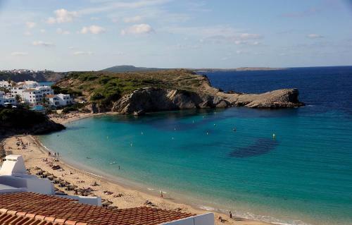 a view of a beach with people in the water at Coves Noves Nice apartment of 75 m2 10 minutes walk from the beach of Arenal d'en Castell in Es Mercadal