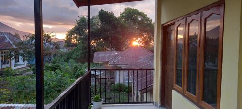 einen Balkon mit Blick auf den Sonnenuntergang von einem Haus aus in der Unterkunft Tange Guest House in Ruteng