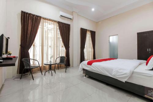 een slaapkamer met een bed en een tafel en stoelen bij RedDoorz At Ralica Grand Palladium Medan in Medan