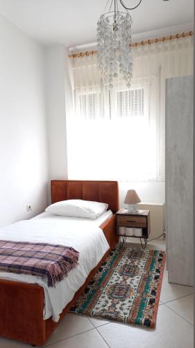 a bedroom with a bed and a table and a chandelier at Isabel's B&B in Tirana
