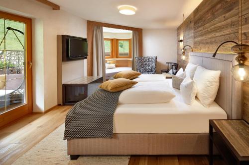 a bedroom with a large bed and a television at ZillergrundRock Luxury Mountain Resort in Mayrhofen
