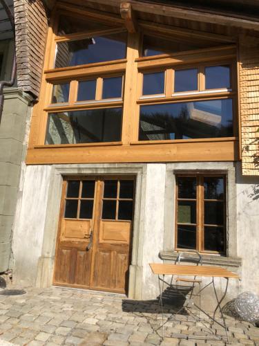 a house with wooden doors and a bench in front of it at Sérénité et nature dans une ferme équestre - studio familial in Massonnens