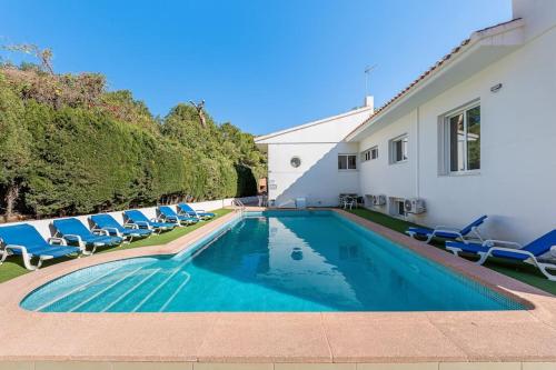 a swimming pool with blue chairs and a house at Entire Large Villa next to Award-winning beach in Campoamor