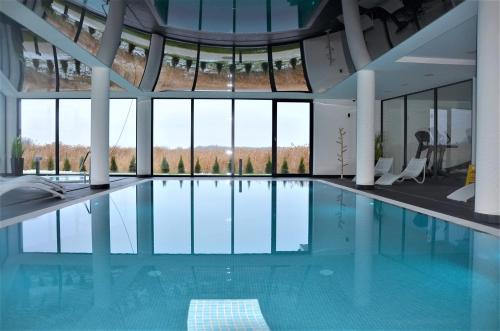 a swimming pool in a building with large windows at Westin House Resort Kołobrzeg Apartament DELUX in Kołobrzeg