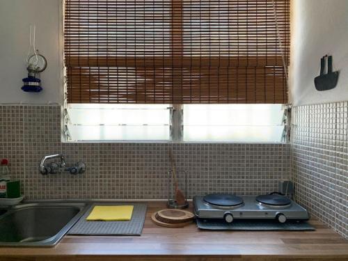 um balcão de cozinha com um fogão e um lavatório em Cosy studio overlooking Porto Germeno gulf em Aigósthena