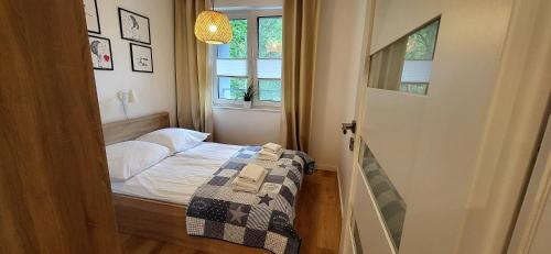 een kleine slaapkamer met een bed en een raam bij Dwie Sosny Apartamenty Ostrowski in Ustronie Morskie