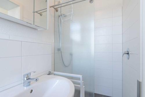 een witte badkamer met een wastafel en een douche bij Villa Marin Wohnung 16 in Zinnowitz