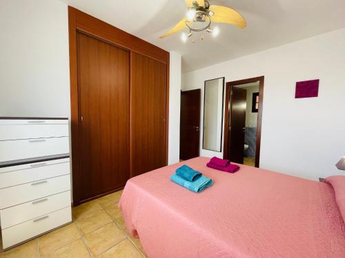 a bedroom with a pink bed with two towels on it at Casa Vista Calma Cotillo Country El Cotillo in Cotillo