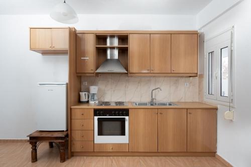 a kitchen with wooden cabinets and a sink at MTC-D Apartments by the Sea and Airport in Porto Rafti