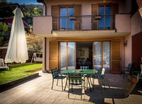 un patio con mesa, sillas y sombrilla en Villino Miralago, en Torno
