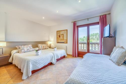 a bedroom with two beds and a tv and a window at Ideal Property Mallorca - Son Morei Gran in Muro