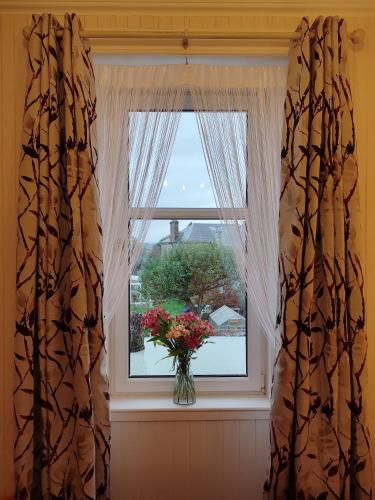 a window with a vase of flowers in a vase at Dunallan Guest House in Perth
