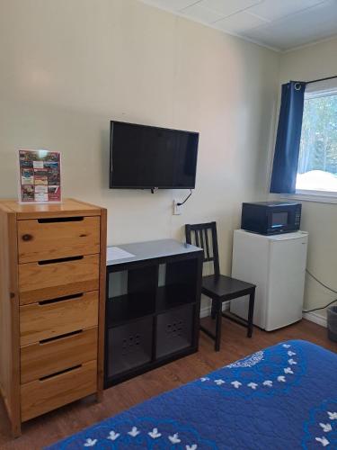 a bedroom with a dresser and a tv on the wall at Three Island Motel in Bobcaygeon