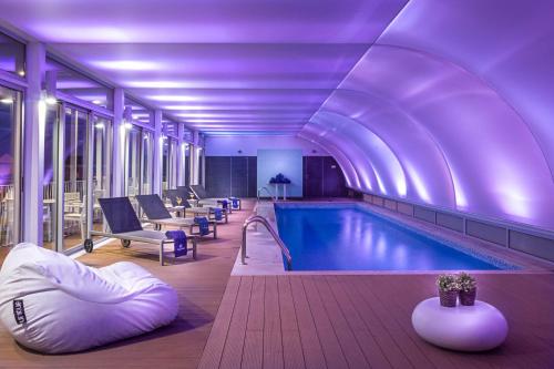 a large swimming pool in a building with purple lighting at Hotel Baia in Cascais