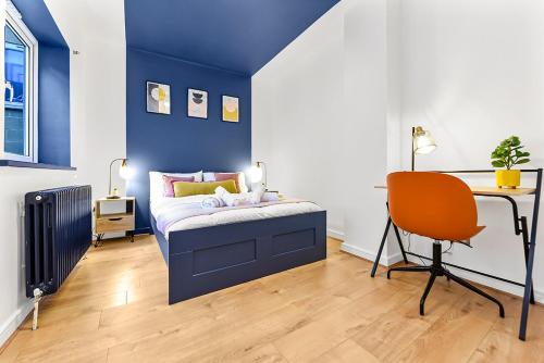 a bedroom with a blue wall with a bed and a desk at Spacious Contemporary 2 bed flat, Central London in London