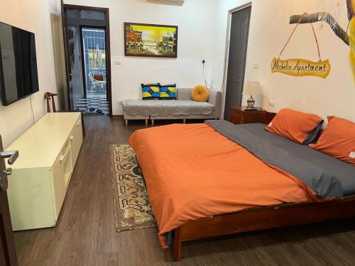 1 dormitorio con 1 cama con edredón de naranja en MICHELIA APARTMENT en Hanói