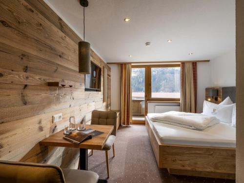 Habitación de hotel con cama y pared de madera en Alpenhof Hotel Garni Suprême en Zell am Ziller