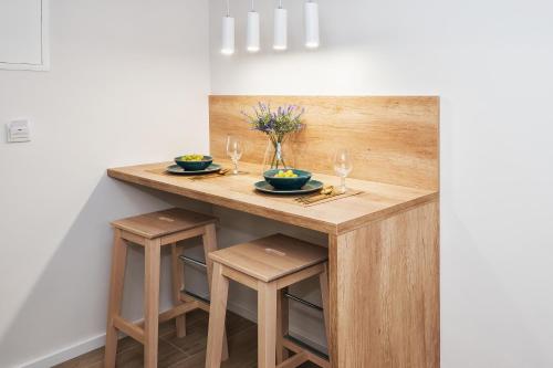 a wooden table with two chairs and two glasses on it at Skalinada Sea View in Lokva Rogoznica