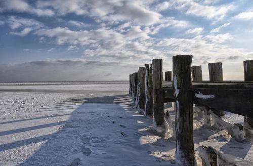 a wooden fence on a beach in the snow at Amrum in Wyk auf Föhr