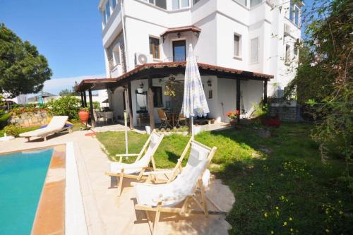 uma casa com piscina e duas cadeiras e um guarda-sol em Bodrum Merkezde Müstakil Havuzlu Villa em Bodrum City