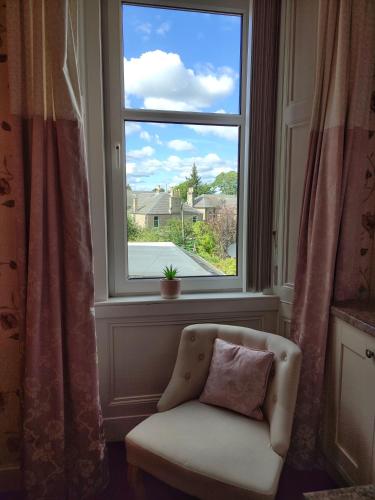 a chair with a pillow sitting in front of a window at Dunallan Guest House in Perth