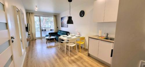 een keuken en een woonkamer met een tafel en stoelen bij Dwie Sosny Apartamenty Ostrowski in Ustronie Morskie