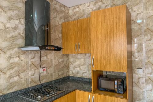 uma cozinha com armários de madeira e uma bancada com um micro-ondas em Rumens Apartment em Lagos