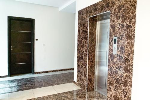 uma casa de banho com uma cabina de duche ao nível do chão ao lado de uma porta em Rumens Apartment em Lagos