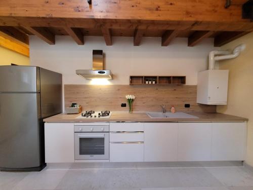 a kitchen with white cabinets and a stainless steel refrigerator at Borgo Antico Lake Endine Hospitality in Endine Gaiano