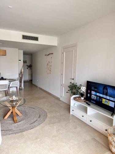 a living room with a tv and a glass table at Aquamarine apartment in Marina Sotogrande in Torreguadiaro
