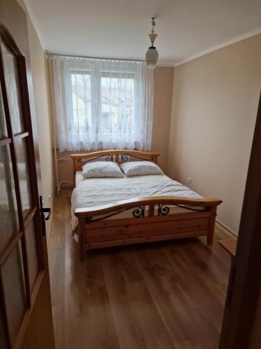 a bedroom with a wooden bed and a window at Apartament blisko Świeradowa in Mirsk