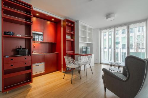eine Küche mit roten Schränken sowie einem Tisch und Stühlen in der Unterkunft easy flat Green Prater in Wien