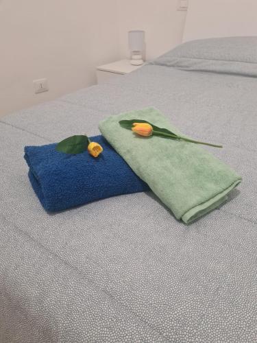 two towels on a bed with two flowers on it at GDB HOUSE in Molfetta
