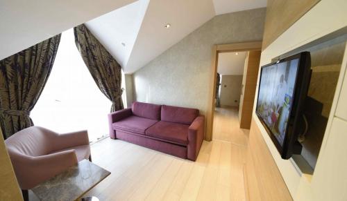 uma sala de estar com um sofá roxo e uma televisão de ecrã plano em Hotel Le Mirage em Istambul