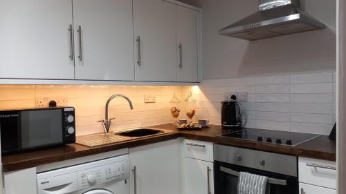 a kitchen with white cabinets and a sink and a microwave at SoulFul Stays Chelmsford in Broomfield