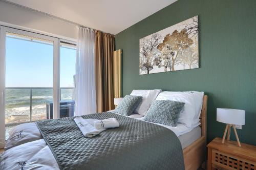 a bedroom with a bed with a view of the ocean at Apartament Szafirowy z BEZPOŚREDNIM WIDOKIEM na morze- Nadmorski Luksus Apartamenty in Ustronie Morskie
