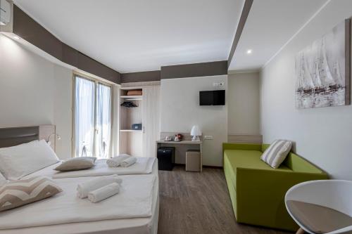 a bedroom with two beds and a green chair at Hotel Imperial ***S in Garda