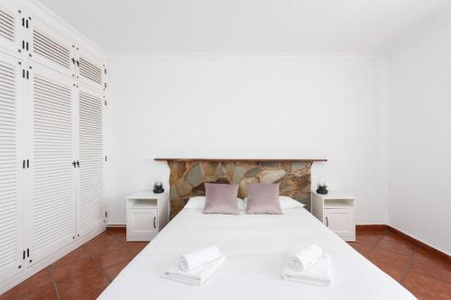 Schlafzimmer mit einem großen weißen Bett und weißen Schränken in der Unterkunft Fantasticas vistas al mar, playa y piscina in Radazul